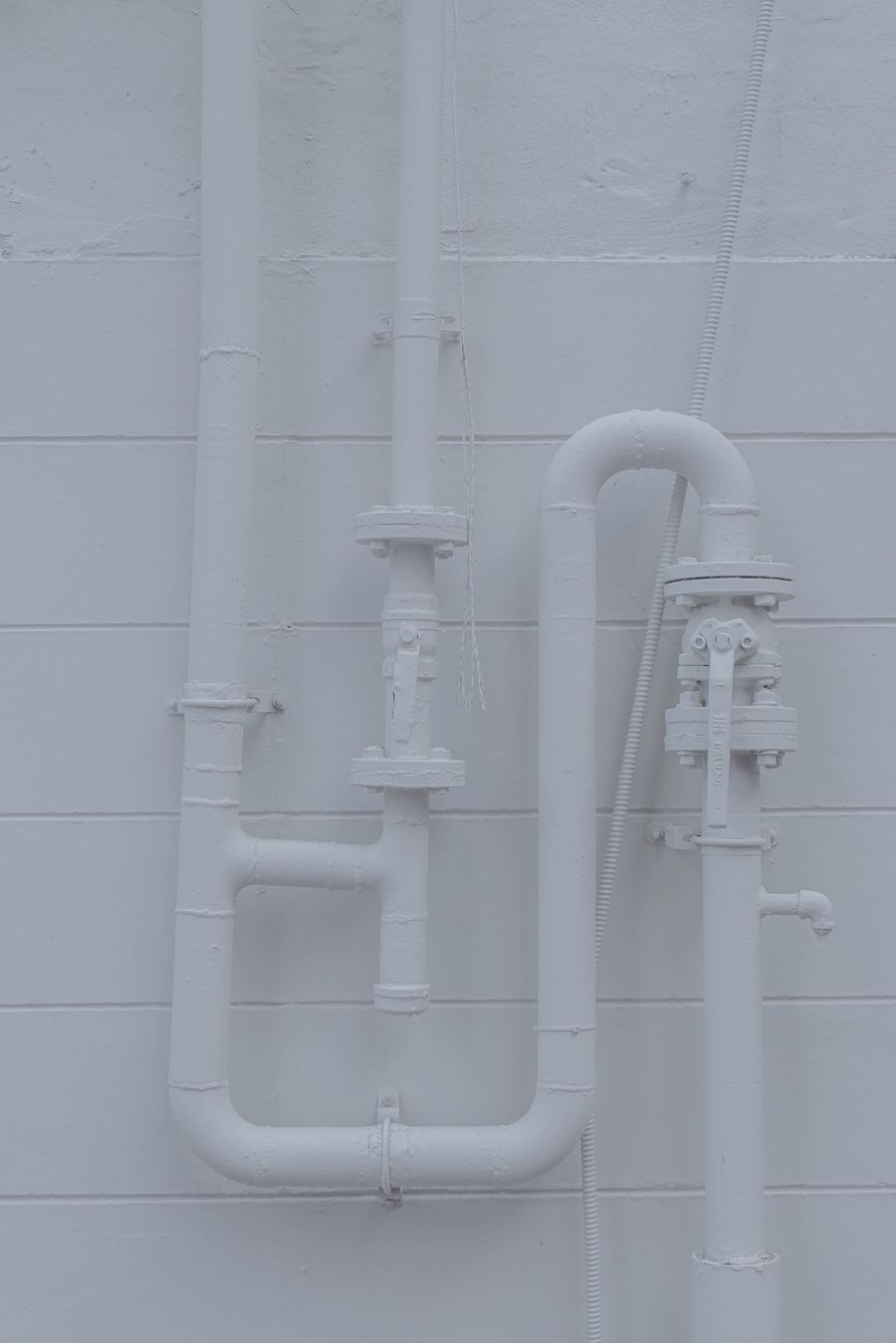 White plumbing pipes and fittings against a tiled wall